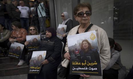 Para pelayat Palestina membawa foto jurnalis Al Jazeera yang terbunuh Shireen Abu Akleh dan berbahasa Arab bertuliskan, Shireen, suara Palestina, di depan kantor saluran Al Jazeera, di kota Ramallah, Tepi Barat, Rabu, 11 Mei 2022 .