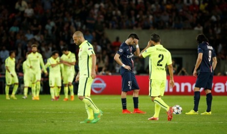 Para pemain Barcelona (kuning) merayakan gol sementara dua pemain Paris Saint-Germain tertunduk lesu.