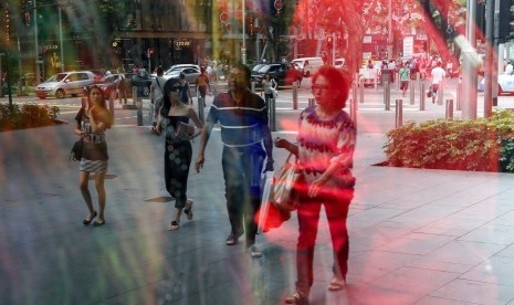 Para pembelanja terlihat dari refleksi sebuah jendela di kawasan Orchard Road, Singapura.