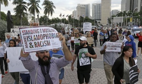 Para pengunjuk rasa meneriakkan slogan menentang perintah kebijakan pemrintahan Presiden Donald Trump terhadap imigran Muslim, Kamis, (26/1), di pusat kota Miami.