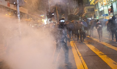 Para pengunjuk rasa pro-demokrasi bereaksi setelah polisi antihuru-hara menembakkan gas air mata selama demonstrasi di Tsim Sha Tsui, Hong Kong, China, Selasa (24/12), atau pada malam Natal 2019.