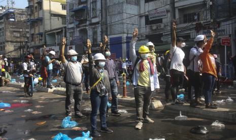  Para pengunjuk rasa yang mengenakan helm pengaman meneriakkan slogan dan memberi hormat tiga jari selama protes anti-kudeta di belakang penghalang di jalan yang diblokir di Yangon, Myanmar, Selasa, 2 Maret 2021. Demonstran di Myanmar turun ke jalan lagi pada Selasa untuk melakukan protes terakhir. bulan perebutan kekuasaan oleh militer, saat menteri luar negeri dari negara-negara Asia Tenggara bersiap untuk bertemu untuk membahas krisis politik. Polisi di Yangon, kota terbesar Myanmar, menggunakan gas air mata untuk melawan para pengunjuk rasa. 