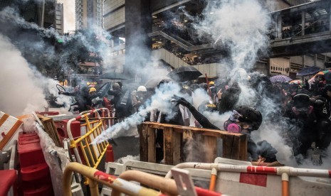 Para pengunjuk rasa yang mengenakan masker gas bereaksi setelah polisi menembakkan gas air mata selama demonstrasi anti-pemerintah di Tsuen Wan, di Hong Kong, Cina, Ahad (25/8).