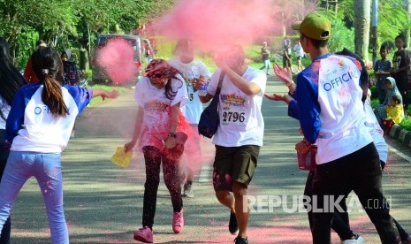 Para peserta lari yang memasuki garis finis ditaburi tepung berwarna pada acara 