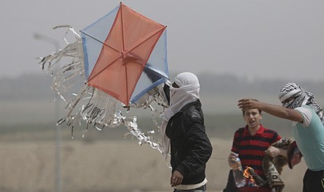 Para remaja Gaza menaikkan layang-layang yang membawa bara api dan minyak untuk dijatuhkan di lahan-lahan Israel selama bentrokan di dekat perbatasan Israel di timur Kota Gaza. 