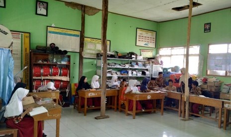 Para siswa belajar di ruangan kelas yang disanggah tiang kayu agar tidak roboh, Kamis (5/12). Tiang kayu itu digunakan sebagai penyangga salah satu ruang kelas di SDN Sirnasari, Desa Sirnasari, Kecamatan Sariwangi, Kabupaten Tasikmalaya, sudah dilakukan sejak tiga tahun terakhir. 