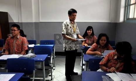   Pengawas mengumpulkan soal dan lembar jawaban para siswa usai mengikuti pelaksanaan ujian nasional (UN) hari terakhir di ruang kelas SMUN 1 Jakarta, Kamis (18/4).   (Republika/Prayogi)