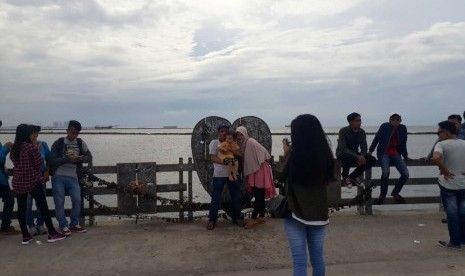 Para wisatawan berfoto di dermaga hati di jembatan cinta Ancol, Jakarta, Senin (26/6).t