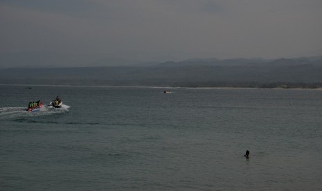 Para wisatawan bermain dan larut dalam keindahan pantai Cilautereun, Garut. 