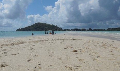 Para wisatawan bermain pasir di Pulau Noko dengan latar belakang Pulau Gili di Bawean, Kabupaten Gresik.