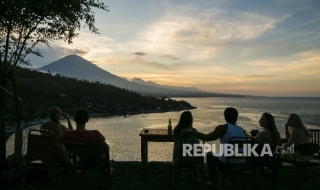 Para wisatawan menyaksikan matahari terbenam di atas Gunung Agung dari desa Amed di Karangasem, Bali, Indonesia (10/10).