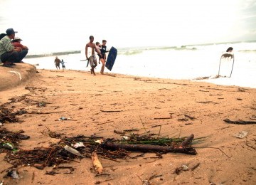 Para wisatawan sedang menikmati pantai Kuta yang dikotori banyak sampah, Ahad (29/1). (Republika/Rusdy Nurdiansyah)