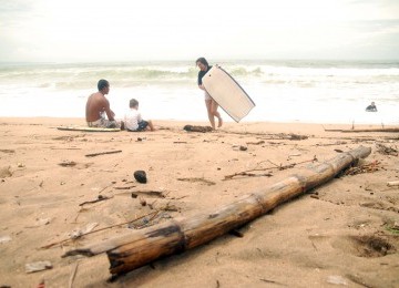 Para wisatawan sedang menikmati pantai Kuta yang dikotori banyak sampah, Ahad (29/1). (Republika/Rusdy Nurdiansyah)