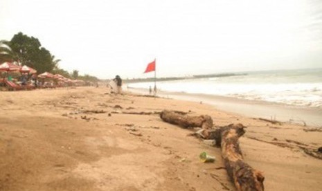 Para wisatawan sedang menikmati pantai Kuta yang dikotori banyak sampah, Ahad (29/1). (Republika/Rusdy Nurdiansyah)