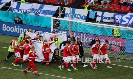 Paramedis menggunakan tandu untuk mengeluarkan Christian Eriksen dari lapangan setelah ia pingsan saat pertandingan grup B kejuaraan sepak bola Euro 2020 antara Denmark dan Finlandia di stadion Parken di Kopenhagen, Denmark, Sabtu (12/6).