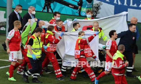 Paramedis menggunakan tandu untuk mengeluarkan Christian Eriksen dari lapangan setelah ia pingsan karena serangan jantung saat pertandingan Grup B kejuaraan sepak bola Euro 2020 antara Denmark dan Finlandia di Stadion Parken di Kopenhagen, Denmark, Sabtu (12/6).