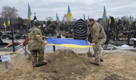 Paramedis Ukraina mengibarkan bendera Nasional makam rekan mereka Valentyna Pushych, yang dibunuh oleh tentara Rusia, di sebuah pemakaman di Kyiv, Ukraina, Sabtu, 5 Maret 2022.