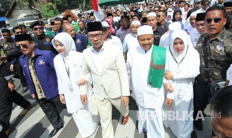 Pasangan calon gubernur dan wakil gubernur Jawa Barat Ridwan Kamil dan Uu Ruzhanul Ulum, bersama istri dan massa pendukungnya berjalan kaki menuju Kantor KPU Jawa Barat, Kota Bandung, Selasa (9/1).