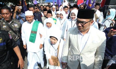 Pasangan calon gubernur dan wakil gubernur Jawa Barat Ridwan Kamil dan Uu Ruzhanul Ulum, berjalan menuntun ibunya menuju massa pendukungnya untuk melaksanakan doa bersama di Lapangan Sidolig, Kota Bandung, Selasa (9/1).