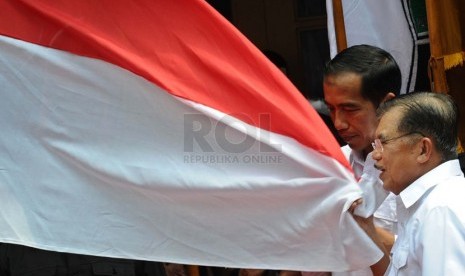   Pasangan Capres-cawapres PDIP Joko Widodo dan Jusuf Kalla mencium bendera merah putih saat deklarasi pasangan capres di Gedung Joang 45, Jakarta, Senin (19/5). (Republika/Tahta Aidilla)