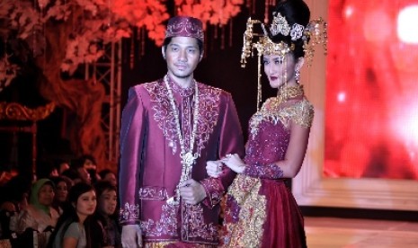 Pasangan pengantin dalam busana adat Betawi modern.