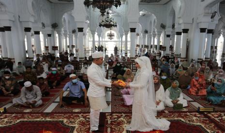 Pasangan pengantin menyerahkan mahar seusai melaksanakan prosesi ijab kabul di Masjid Raya Baiturrahman, Banda Aceh, Aceh, Kamis (23/9/2021). Selama pandemi COVID-19. Jangan Sampai Ada Klaster Nikah, KUA Diminta Koordinasi dengan Satgas Covid-19