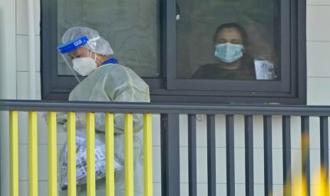 Pasien menerima obat dari tenaga kesehatan di fasilitas isolasi di Lantau Island, Hong Kong, Kamis (24/2/2022).