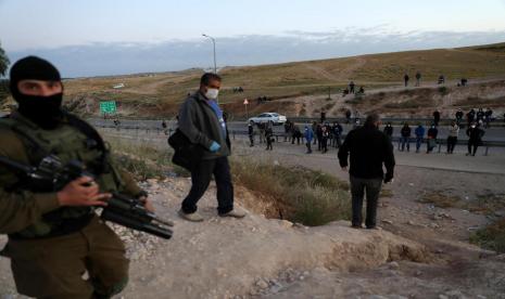  Pasukan Militer Israel mencegah seorang buruh Palestina memasuki wilayah Israel setelah secara ilegal melintasi pagar keamanan Israel di dekat kota Hebron Tepi Barat, Selasa (5/5). Pekerja Palestina mencoba memasuki area perbatasan Israel untuk bekerja setelah larangan masuk diberlakukan di tengah kekhawatiran atas penyebaran pandemi COVID-19. 