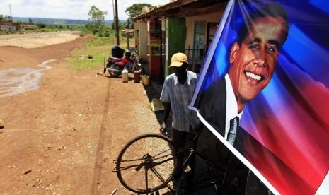   Paul Opiyo Ojwang, pria berusia 43 tahun warga desa Kogelo memasang poster Barack Obama di depan bengkel sepeda miliknya di desa Kogelo, Nyangoma, Kenya, Senin (5/11).     (Reuters/Thomas Mukoya) 