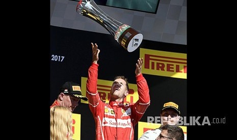 Pebalap Ferrari Sebastian Vettel merayakan kemenangannya pada Grandprix Hongaria di Sirkuit Hongaroring, Hongria, Ahad (30/7).