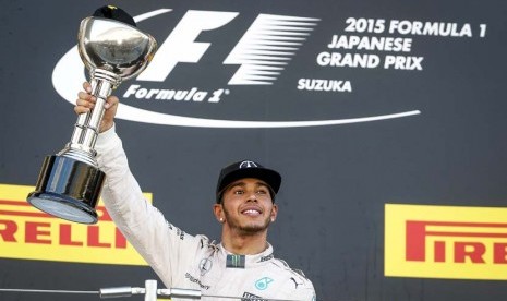 Pebalap Mercedes asal Inggris, Lewis Hamilton, mengangkat trofi usai menjuarai balapan Formula 1 seri GP Jepang di Sirkuit Suzuka, Jepang, Ahad (27/9). 