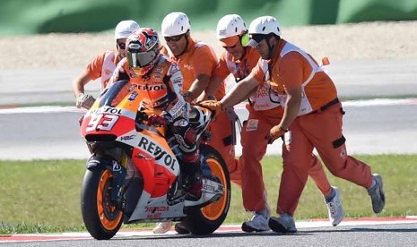 Pebalap Spanyol, Marc Marquez, dibantu memasuki kembali lintasan balapan setelah sempat terjatuh saat balapan Motogp seri GP San Marino di Sirkuit Misano, Italia, Ahad (14/9). 