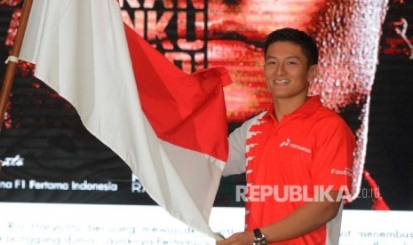  Pebalap Tim Manor Racing Formula 1 Rio Haryanto (kanan), menerima bendera Indonesia dari Menteri Pemuda dan Olahraga Imam Nahrawi (kiri), saat menggelar konferensi pers di Jakarta, Kamis (18/2).