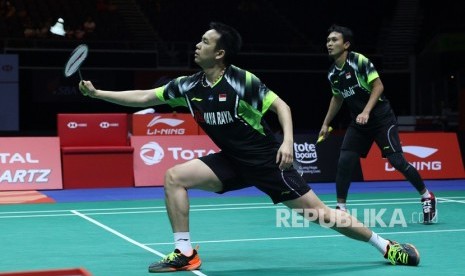 Pebulutangkis ganda putra Indonesia Hendra Setiawan (kiri) mengembalikan kok disaksikan rekannya Mohammad Ahsan saat laga final turnamen Singapura Terbuka 2018 melawan pasangan Cina Ou Xuanyi/Xiangyu di Singapore Indoor Stadium, Ahad (22/7). 