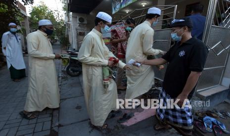 Pecalang atau petugas keamanan desa adat memeriksa suhu tubuh jemaah yang akan beribadah Shalat Idulfitri 1442 Hijriah di Mushola Silaturrahmi, Denpasar, Bali, Kamis (13/5/2021). Salat Idulfitri di tempat tersebut melibatkan pecalang untuk menjaga keamanan dan kenyamanan umat Islam saat menjalankan ibadah.