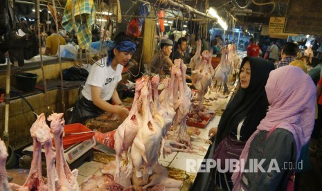 Pedagang daging ayam melayani pembeli.