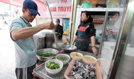 Pedagang kaki lima pho atau sup mi Vietnam sedang meracik semangkuk pho.