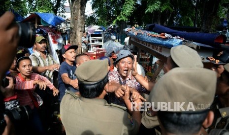  Pedagang kaki lima (PKL) berteriak menolak gerobaknya dibawa oleh petugas Pol PP di kawasan Kota, Jakarta, Selasa (25/10).  (Republika/Prayogi)