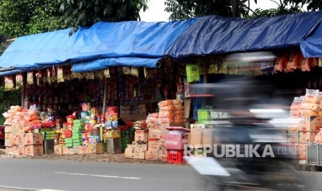 Pedagang Kue menata barang dagangangannya sambil menunggu pembeli di kios semi permanen di Jalan Raya Bogor, Jakarta Timur, Senin (20/6). (Republika/Rakhmawaty La'lang)