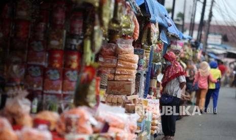 Pedagang Kue menata barang dagangangannya sambil menunggu pembeli di kios semi permanen di Jalan Raya Bogor, Jakarta Timur, Senin (20/6).