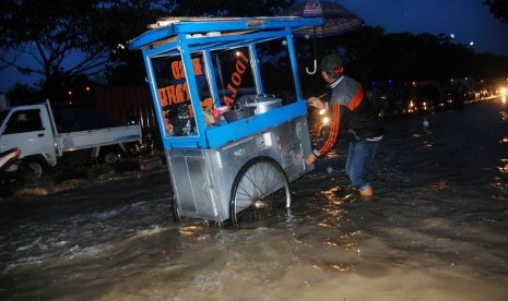 Pedagang melewati banjir di Gedebage, Bandung, Jawa Barat, Jumat (28/10). 