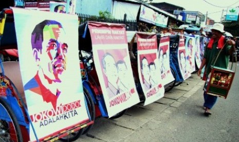 Pedagang melintas di barisan becak bergambar Capres Joko Widodo, di Jl Prabu Siliwangi, Pamulang,Tangerang Selatan, Banten, Sabtu (7/6).