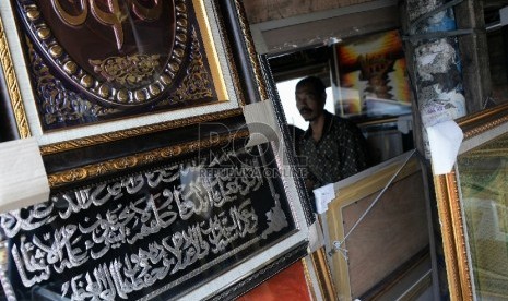 Pedagang memberishkan hiasan kaligrafi dinding di Kawasan Pasar Baru, Jakarta, Kamis (30/7). 