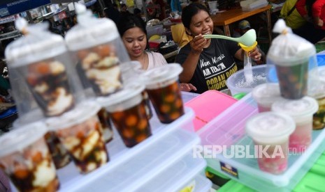 Pedagang membungkus minuman untuk dijual di Pasar Takjil Benhil, Jakarta, Senin (6/5/2019).