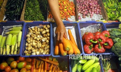 Pedagang menata sayur mayur di pasar tradisional. 