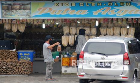 Pedagang menawarkan makanan di pusat oleh-oleh kawasan Puncak, Kabupaten Bogor, Jawa Barat, Jumat (13/8/2021). Penjualan oleh-oleh di kawasan Puncak, Bogor mengalami penurunan sebesar 80 persen dampak sepinya wisatawan lokal di jalur wisata tersebut di masa PPKM.