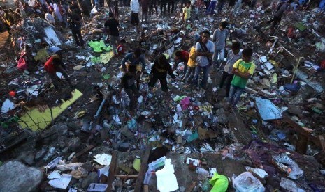 Pedagang mengumpulkan barang yang masih dapat digunakan dari puing-puing bangunan pasar Meuredu yang rubuh akibat gempa di Pidie Jaya, Aceh, Kamis (8/12). 