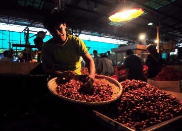 Pedagang mengupas bawang merah sebelum dijual di Pasar Induk Kramat Jati, Jakarta, Ahad (29/1). (Republika/Edwin Dwi Putranto)