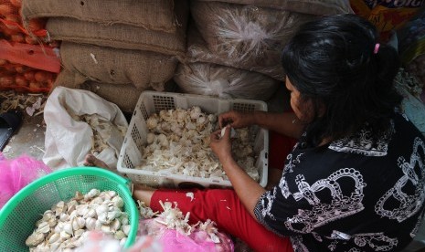 Pedagang mengupas kulit bawang putih di pasar tradisional. ilustrasi