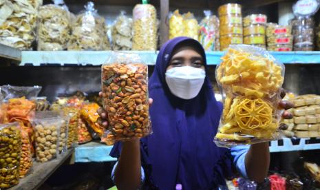 Pedagang menunjukkan camilan atau makanan ringan di Pasar Brayung, Mejobo, Kudus, Jawa Tengah, Kamis (21/4/2022). Menurut pedagang, penjualan berbagai macam camilan seperti olahan keripik tahu dan tempe dan roti kering hingga berbagai olahan kacang itu penjulan naik hingga 50 persen dibanding hari biasa dan diprediksi akan terus meningkat menjelang hari raya Idul Fitri. 